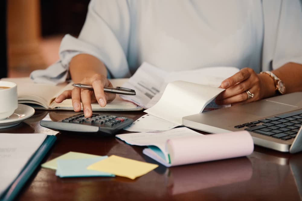 personne qui fait un calcul avec des documents sur un bureau avec ordinateur